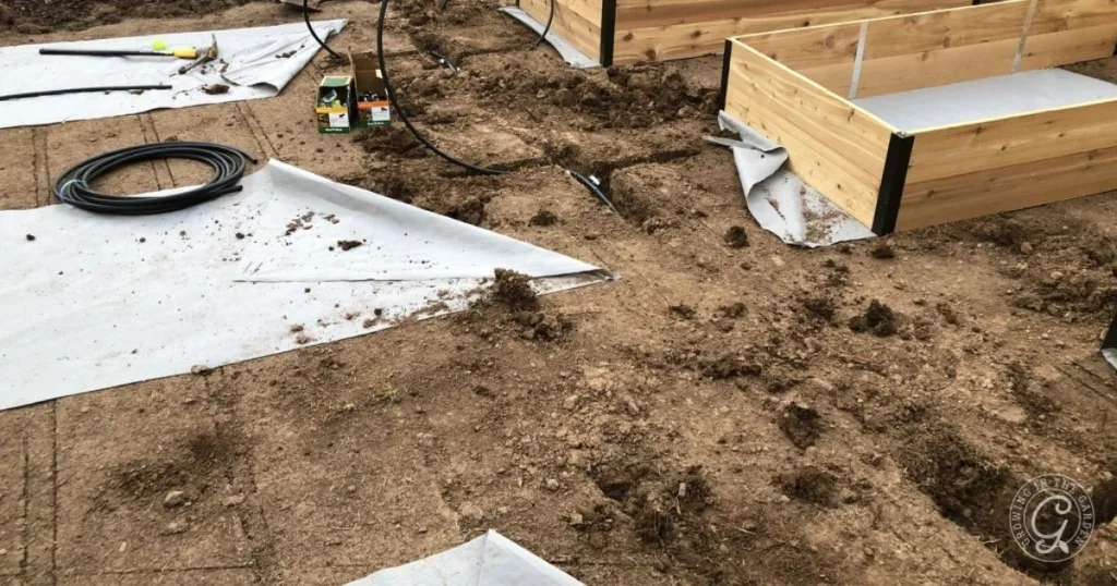 Raised Garden Beds being assembled on soil, with landscape fabric and garden tools nearby, showcase an efficient Raised Bed Garden Design for your outdoor space.