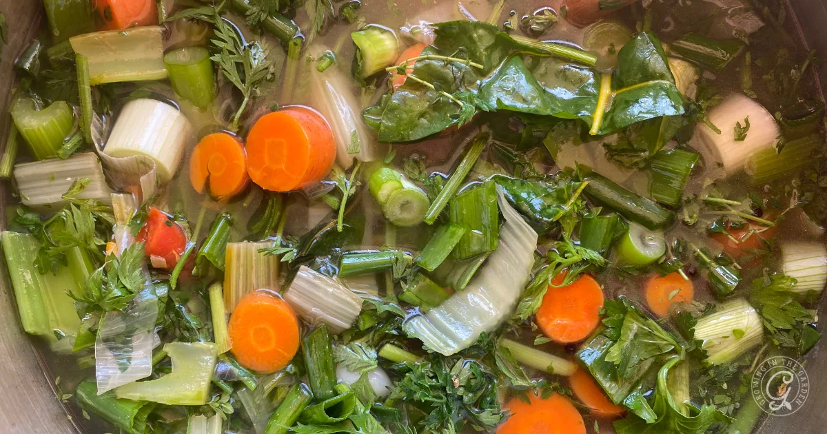 Chopped carrots, celery, onions, and greens simmering in water to create a flavorful garden vegetable broth & stock.