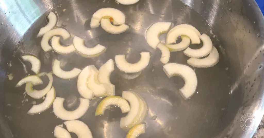 Sliced onions in water inside a stainless steel pan&mdash;an essential prep step found in some of the best recipes for Anna apples.