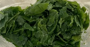 Close-up of frozen, chopped spinach leaves inside a plastic bag&mdash;similar to how to freeze basil for long-term freshness.