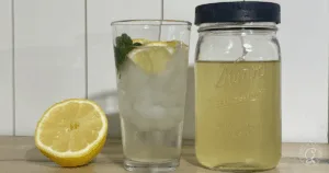 A glass of iced lemonade with mint and lemon slices, a mason jar of lemonade, and half a lemon on a table&mdash;refreshing sips to enjoy while browsing the Best Recipes for Okra.