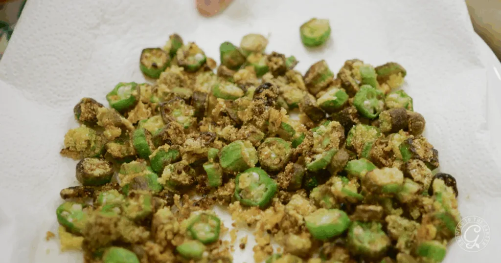Crispy, golden-brown fried okra pieces rest on a paper towel.