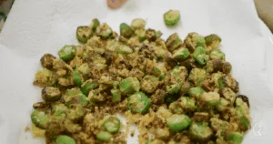 Crispy, golden-brown fried okra pieces rest on a paper towel&mdash;an irresistible snack and a classic choice among the best recipes for okra.