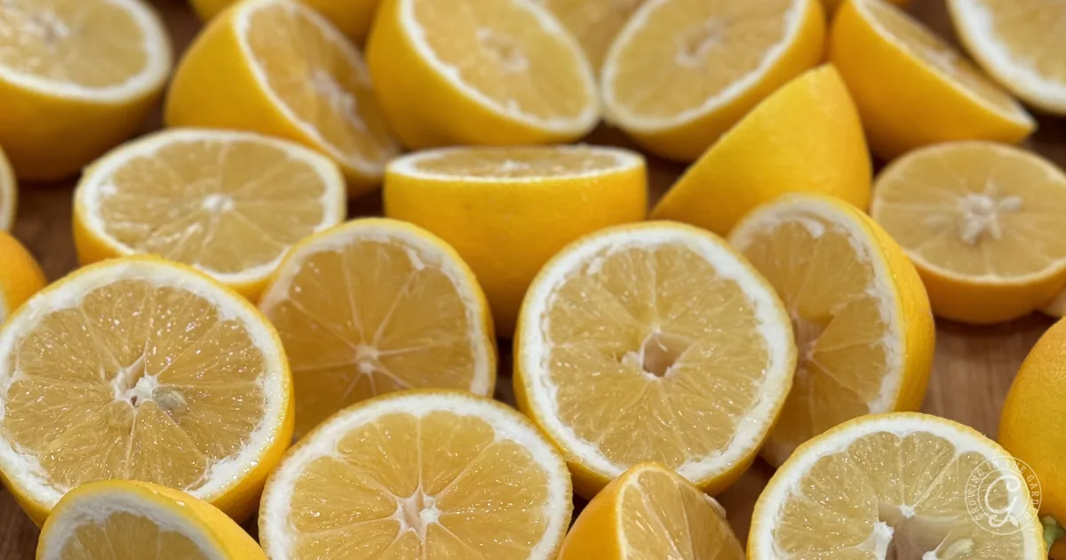 Several yellow lemons cut in half, displayed closely together with juicy interiors visible.