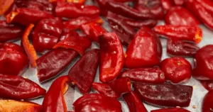 Close-up of roasted peppers, their vibrant red pieces spread out on a metallic surface.