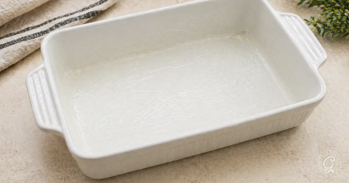 Rectangular white ceramic baking dish greased with butter.
