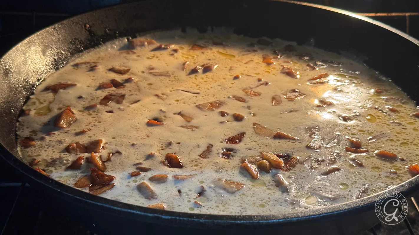 Apple Dutch baby batter baking over cinnamon apples in a cast iron skillet.